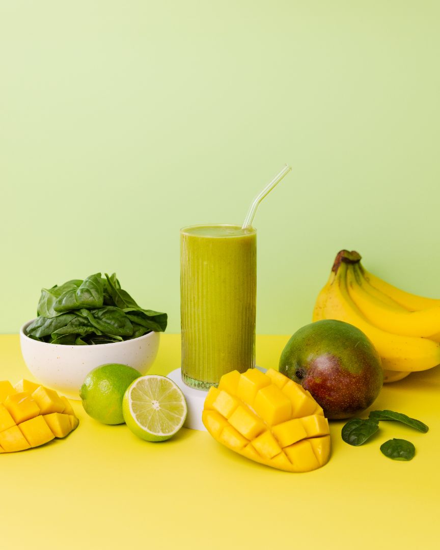 Healthy green smoothie made with Booster ready-to-blend pack and ingredients on table
