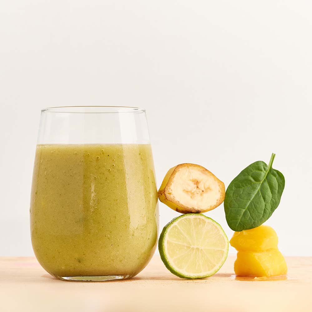 Healthy smoothie made with Booster ready-to-blend pack and ingredients on table