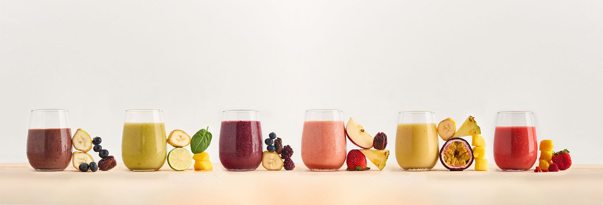 Colourful healthy smoothies in glasses with ingredients beside them from the Serious Smoothies Cafe Range